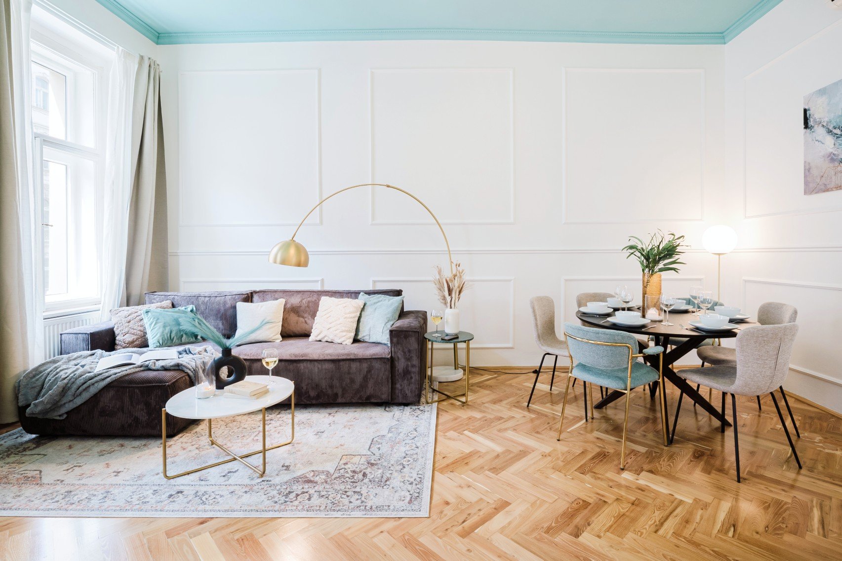 Megvalósítás: a színesen kiemelt mennyezet, a természetes fény és a textúrák rétegzése egyszerre kölcsönöz könnyedséget és otthonosságot a belső térnek.