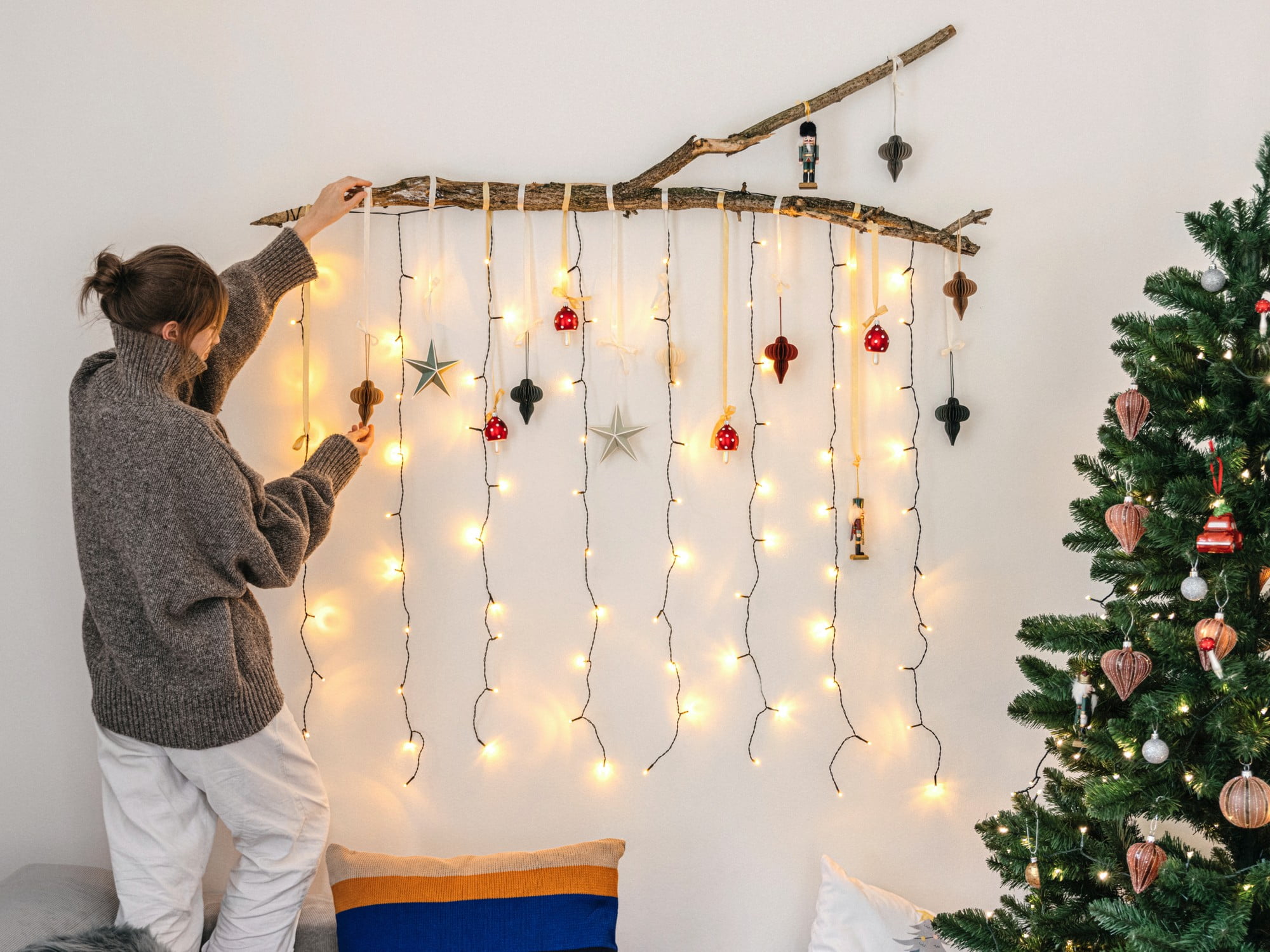 Ehhez a karácsonyi dekorációhoz mindössze egy ágra, néhány díszre és fényfüzérekre van szükséged.