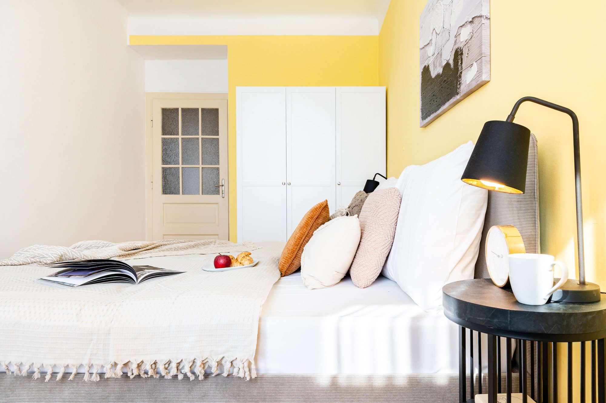 A tér friss, optimista és harmonikus hatású, amelyet a meleg sárga akcentus, a rétegzett textíliák és az apró részletek tesznek otthonossá.